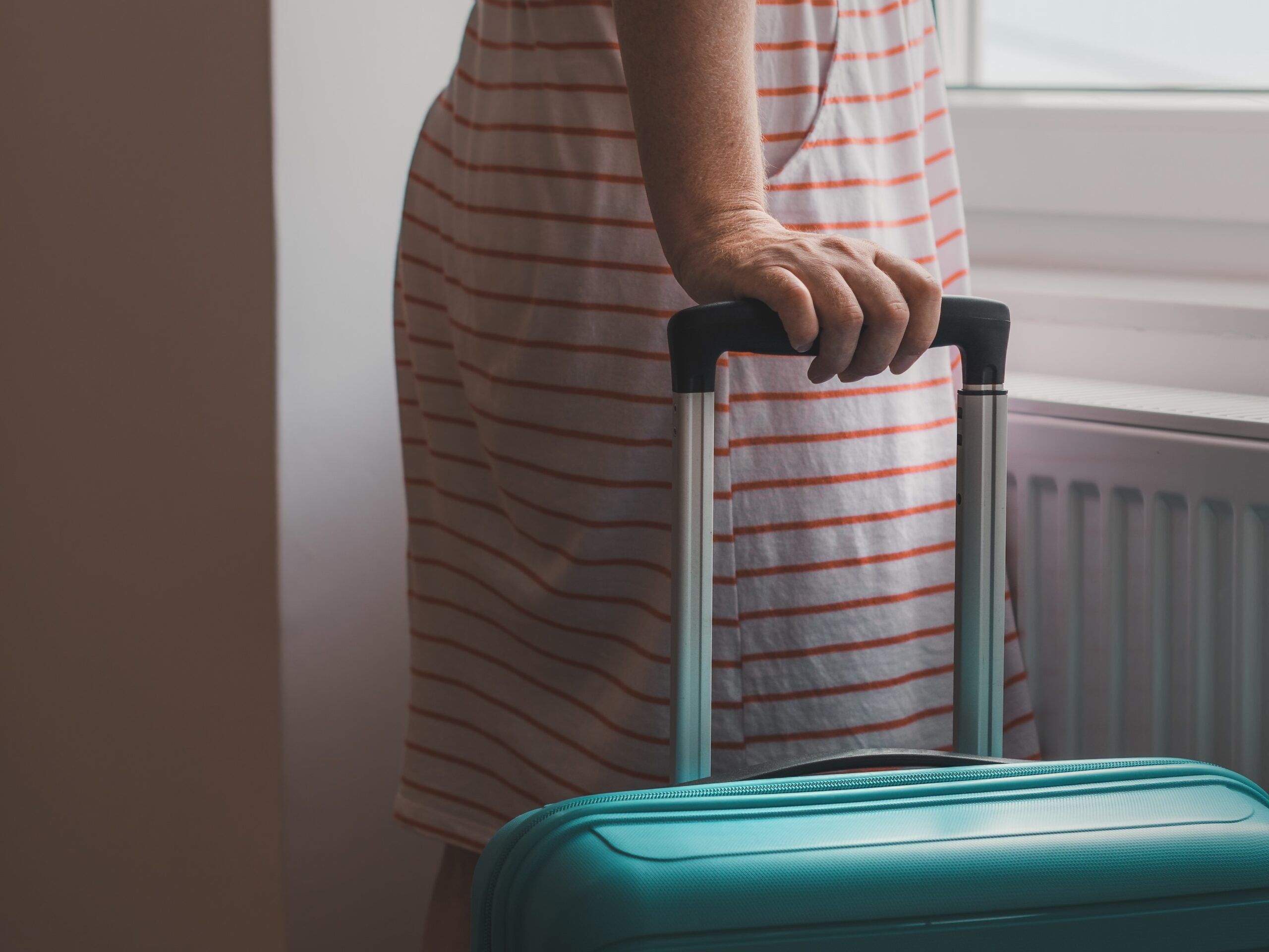 Female tourist pulling travel luggage suitcase into apartment room